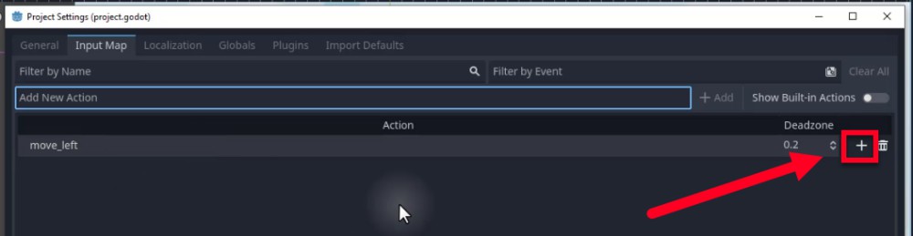 Aquesta imatge mostra la finestra de configuració del projecte del motor Godot per a "project.godot", amb la pestanya "Mapa d'entrada" activa, mostrant l'acció creada recentment "move_left" a la llista. Una fletxa i un quadre vermells destaquen el botó més (+) al costat dret de la fila "move_left"; aquest és el control utilitzat per assignar tecles d'entrada (com la fletxa esquerra o A) a l'acció, tal com es descriu a la lliçó per mapejar controls sense codificar tecles específiques en scripts. El valor de Deadzone de 0,2 també és visible al costat del nom de l'acció, que indica una configuració de sensibilitat configurable per a les entrades analògiques.